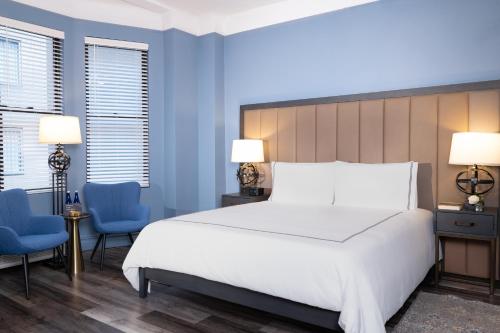 a bedroom with a large white bed and two blue chairs at Kixby in New York