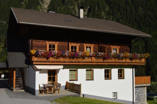 ein Haus mit einem Balkon mit Blumen darauf in der Unterkunft Ferienwohnungen Niederarnigerhof Familie Bauernfeind in Kals am Großglockner