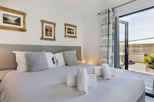 a bedroom with a large white bed with a balcony at 3 Bed in Woolacombe oc-s29615 in Woolacombe