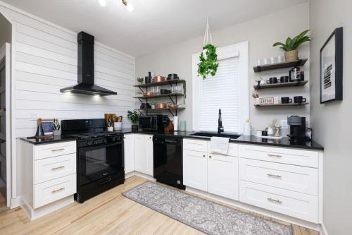 a kitchen with white cabinets and black appliances at Walk to Highland Square, Sleeps 8 in Akron