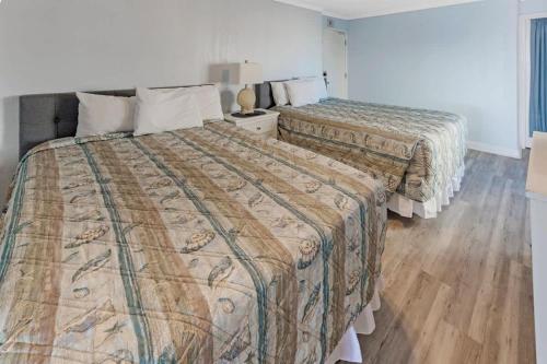 two beds in a hotel room with wooden floors at 1BR Direct Oceanfront Views at Palms - Nice Pools! in Myrtle Beach