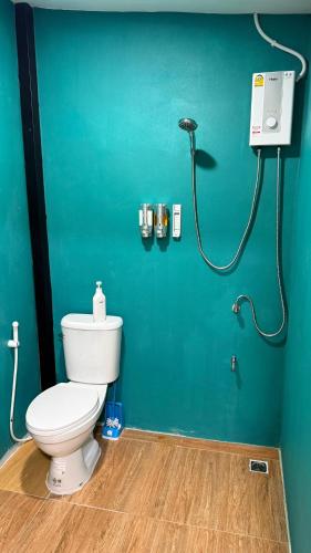 a bathroom with a toilet and a green wall at So Cute Hostel, Kai Bae, Koh Chang in Trat
