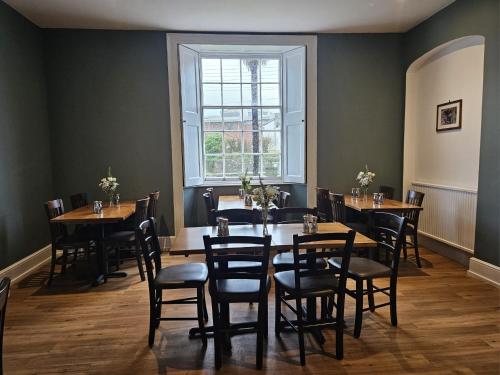 a dining room with tables and chairs and a window at The White House Hotel in Williton