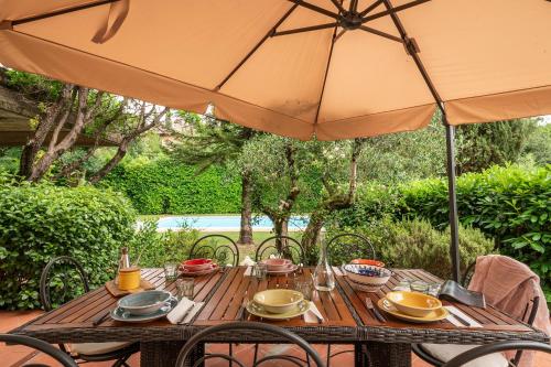 a wooden table with an umbrella on a patio at Villa Monica in Le Bolle