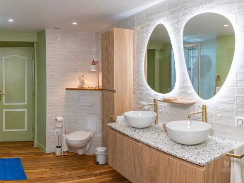 a bathroom with two sinks and a toilet and a mirror at Gite le Mont Blanc in Le Mesnil-sur-Oger