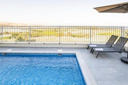 a swimming pool on a balcony with chairs and an umbrella at וילה קלמה מגדל in Migdal