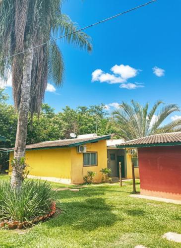 ein gelb-rotes Haus mit einer Palme in der Unterkunft Suíte Aconchegante na Natureza - RepousaAquiÓ in Olímpia