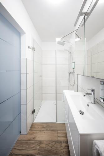 a white bathroom with a shower and a sink at Hotel Magnolie GmbH in Laufenburg