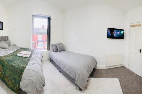 a bedroom with two beds and a window at Manchester City Cosy Stay - Fresh New Master bedroom Sleeps 3 Guests - 3 Adults in Manchester
