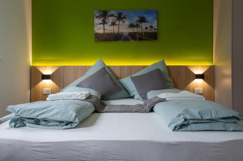 a large bed with two pillows and a green wall at Luani appartments in Krefeld
