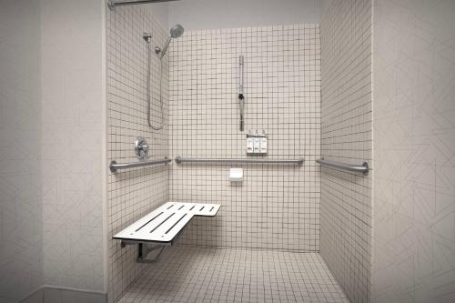 a white tiled shower with a bench in a bathroom at Holiday Inn Express Fargo - West Acres by IHG in Fargo