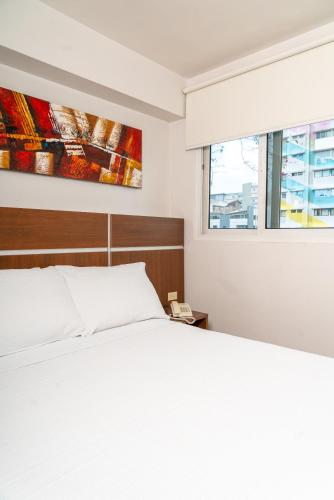 a bedroom with a white bed and a window at Hotel Benidorm Panama in Panama City