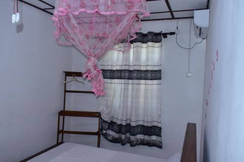 a bedroom with a bed with a pink curtain at Upali Homestay in Kandy
