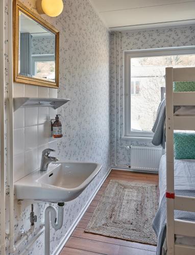 a bathroom with a sink and a bed and a window at Klippen Hotel - Therns in Gudhjem