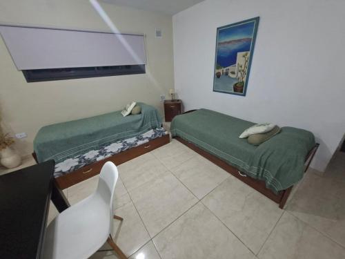 two beds in a room with a table and a chair at paraíso lomas in San Antonio de Arredondo