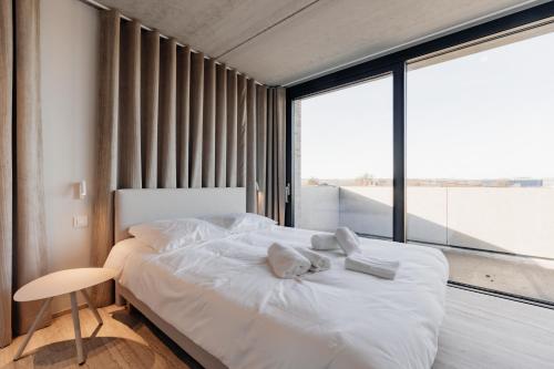 a bedroom with a white bed and a large window at Coliving - Bord de Meuse - L'instant in Oupeye