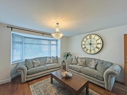 a living room with a couch and a clock on the wall at The Annexe in Peacehaven