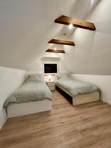 a attic bedroom with two beds and a window at Ferienhaus am Bürgergarten in Bad Bentheim