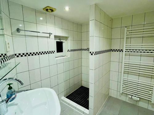 a white tiled bathroom with a shower and a sink at Ferienhaus am Bürgergarten in Bad Bentheim