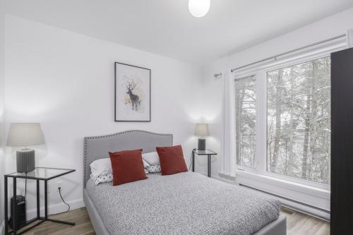a white bedroom with a bed and a window at NatureX Spa River Dogfriendly in Sainte Béatrix