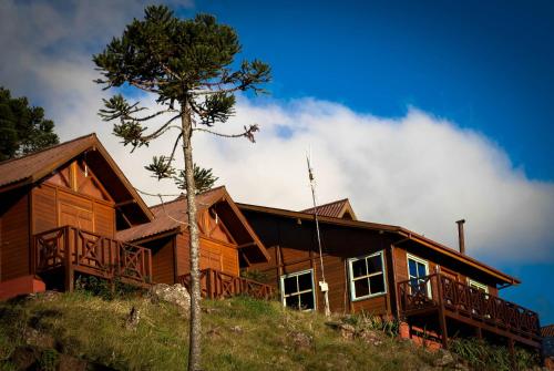 a house on a hill with a tree in front of it at Pousada Fogo Eterno in Urubici