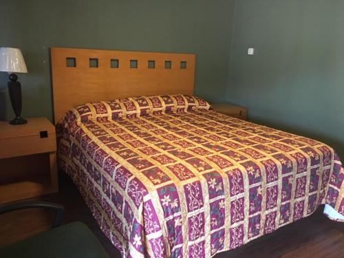 a bed with a colorful comforter in a bedroom at Townhouse Motel - West Sacramento in West Sacramento