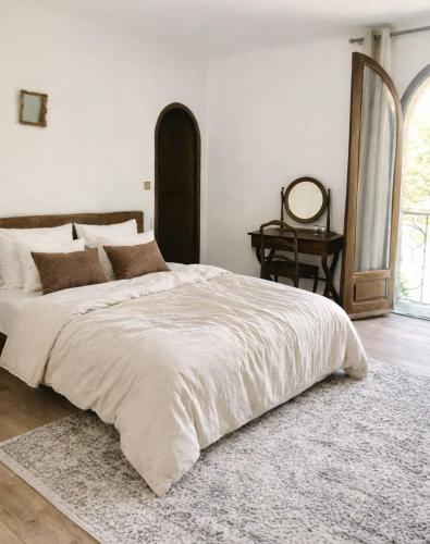 a bedroom with a large white bed with a rug at Chambres de charme - 2 chambres indépendantes avec salles de bains privatives in Corte