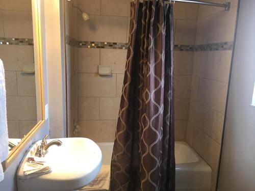 Baño con cortina de ducha junto a un lavabo y una bañera en Townhouse Motel - West Sacramento, en West Sacramento