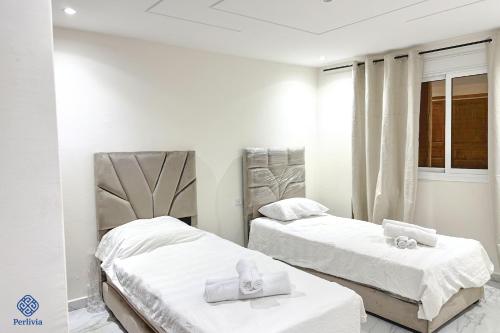 two beds in a room with white walls at Perlivia in Chefchaouen