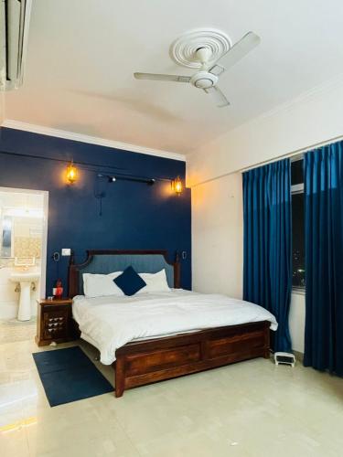 Vantage View - 2BHK Apartment في Nalmatha: غرفة نوم بها سرير وجدار أزرق
