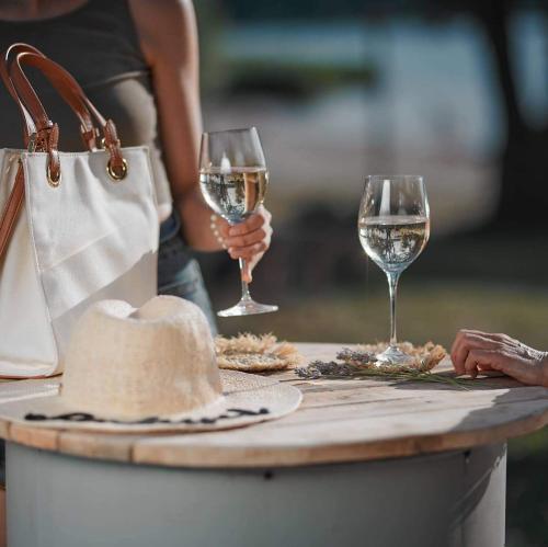 ein Tisch mit zwei Gläsern Weißwein und einer Handtasche in der Unterkunft Chill Camp in Giewartów