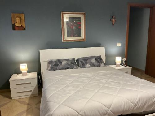 a bedroom with a white bed with two night stands at Lucia's House - Relax nel cuore del Salento in Lequile