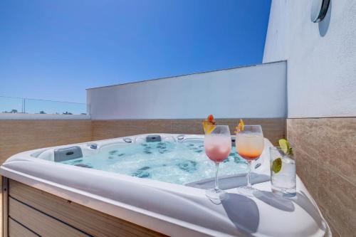 two glasses of wine in a hot tub at Bayside A Apartments in St. Julianʼs
