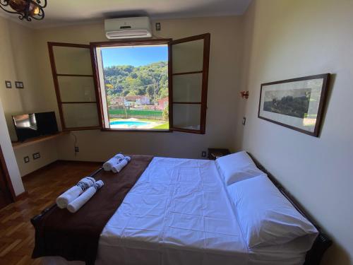 a bedroom with a large bed and a window at Casa Vale da Serra - Petrópolis in Petrópolis