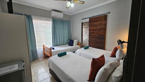 a hotel room with two beds and a window at Honey Bee Guesthouse in Rustenburg
