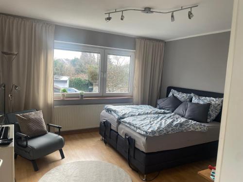 a bedroom with a bed and a chair and a window at Gemütliches Appartement Köln in Cologne