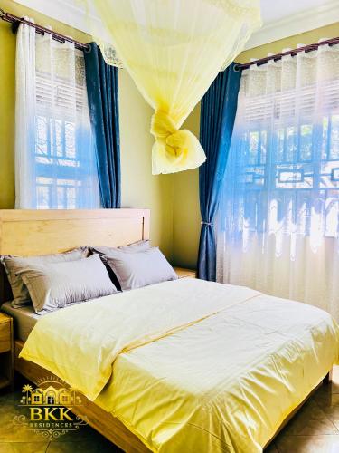 a bedroom with a large bed with blue curtains at BKK Residences in Fort Portal