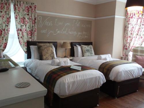 a bedroom with two beds and a sign on the wall at Hooray Henrys Sheringham in Sheringham