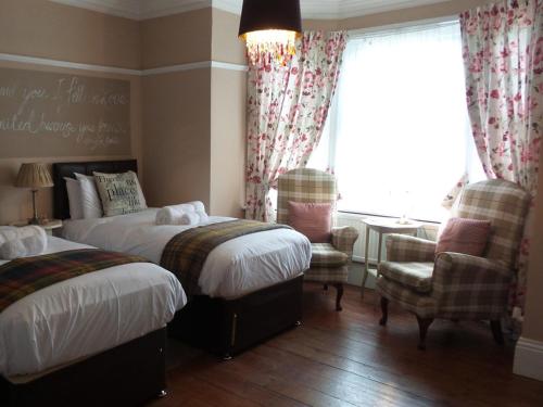 a bedroom with two beds and a chair and a window at Hooray Henrys Sheringham in Sheringham