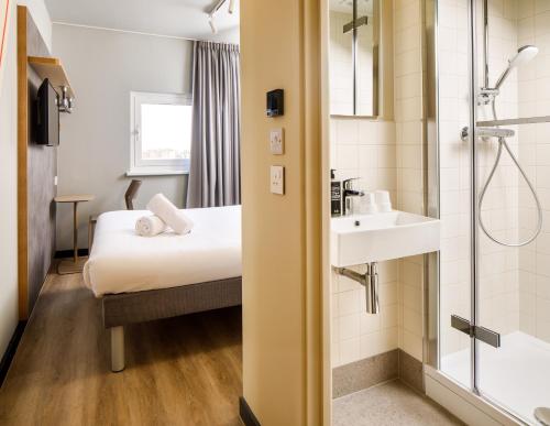 a bathroom with a bed and a sink and a shower at ibis budget Birmingham Centre in Birmingham