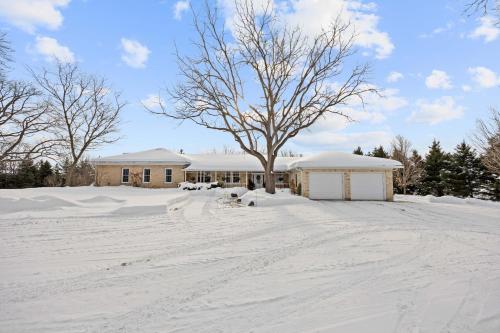 a snow covered yard with a house and a tree at Farmhouse Stay Guelph Elora in Guelph