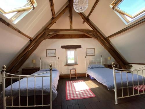 two beds in a attic bedroom with skylights at Chez le Cavalier in Génis