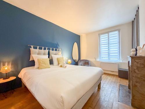 a bedroom with a large white bed with a blue wall at Les Volets Bleus in Chartres