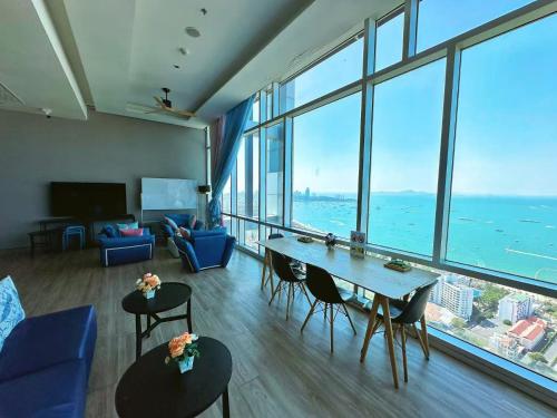 a living room with a table and chairs and large windows at Pattaya Sea View Condo in Pattaya