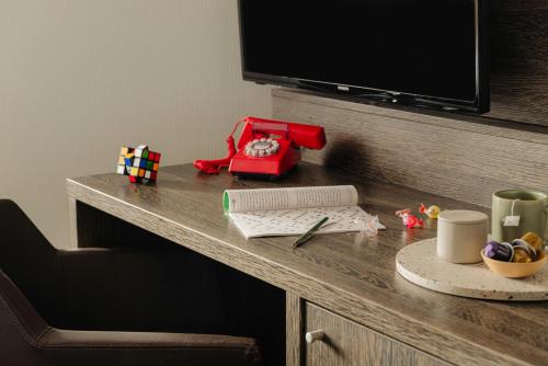 a desk with a television and a table with a keyboard at Leonardo Hotel Eindhoven City Center in Eindhoven