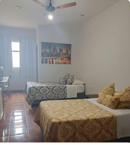 a hotel room with two beds and a ceiling fan at Gutemberg Palace Hotel in Nova Serrana
