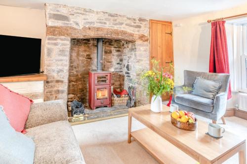 a living room with a stone fireplace and a table at 2 Bed in Defynnog oc-t32724 in Sennybridge