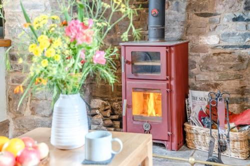 a table with a vase of flowers and a stove at 2 Bed in Defynnog oc-t32724 in Sennybridge