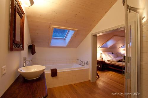 a bathroom with a tub and a sink and a bedroom at Le Jardin de Kabir in Martigny-Ville