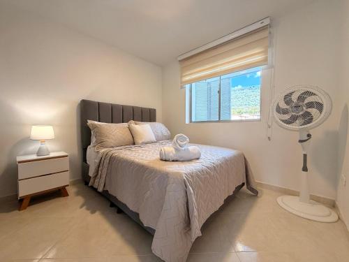a bedroom with a bed with a fan and a window at Espacio cómodo, piscina, jacuzzi y parqueadero in San Gil